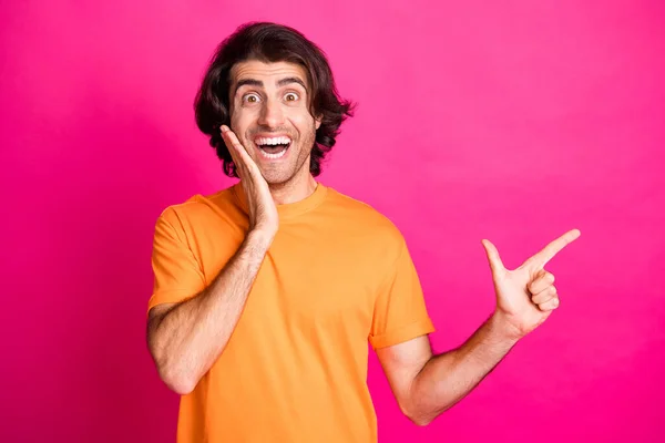 Φωτογραφία του άνδρα άμεσο δάχτυλο κενό χώρο βραχίονα ζυγωματικό φορούν πορτοκαλί t-shirt απομονωμένο ροζ χρώμα φόντο — Φωτογραφία Αρχείου