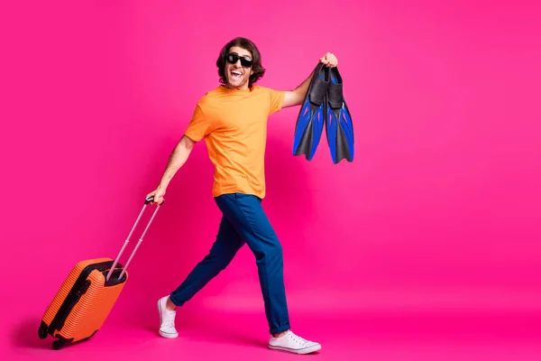 Foto de perfil de comprimento total do homem andar porão bagagem vira desgaste laranja t-shirt jeans sunglass sneakers isolado cor-de-rosa fundo — Fotografia de Stock