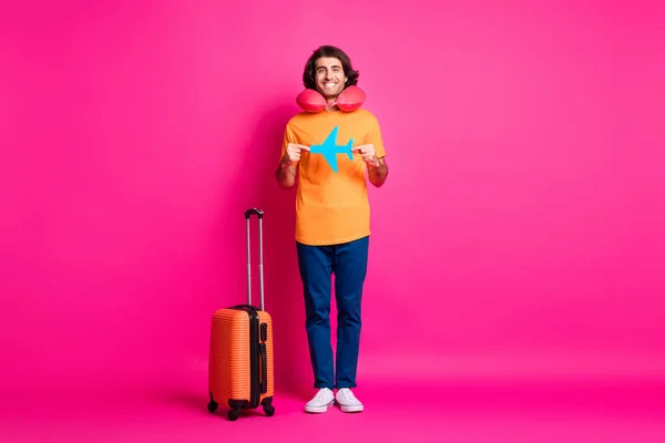 Foto de comprimento total de cara bagagem demonstrar papel avião desgaste pescoço almofada laranja t-shirt jeans tênis isolado cor-de-rosa fundo — Fotografia de Stock