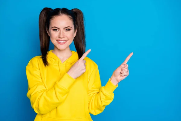 Photo of attractive lady two tails hairstyle direct fingers side empty space sale shopping banner low prices wear casual yellow hoodie pullover isolated bright blue color background — Zdjęcie stockowe