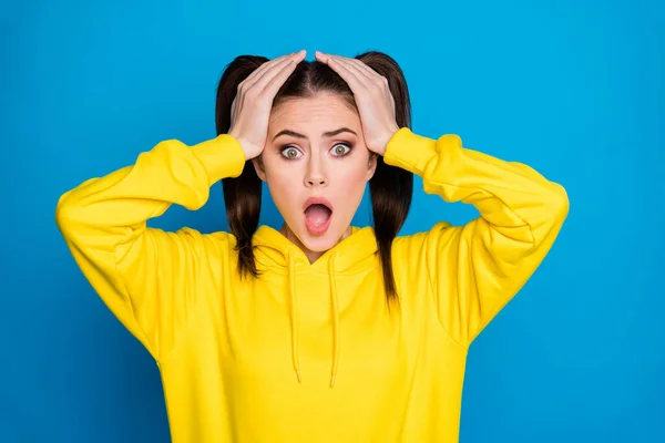 Photo of attractive shocked lady funny two tails hairdo open mouth watch news quarantine continue arms on head wear casual yellow sweatshirt pullover isolated bright blue color background — Stock Photo, Image