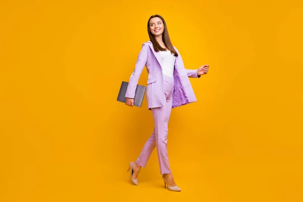 Teljes méretű profil fotó gyönyörű üzleti vezérigazgató hölgy gazdaság notebook kéz megy irodai épület dolgozni konferencia viselet lila iroda jelmez elszigetelt sárga szín háttér — Stock Fotó