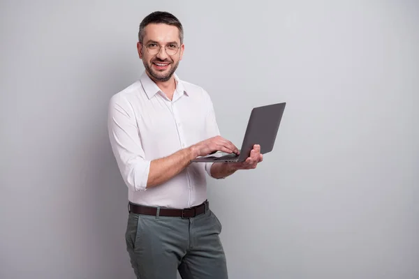 Portrét jeho hezký atraktivní veselý veselý úspěšný zralý muž drží v ruce notebook vytváří web design prezentace izolované přes světle šedé pastelové barvy pozadí — Stock fotografie