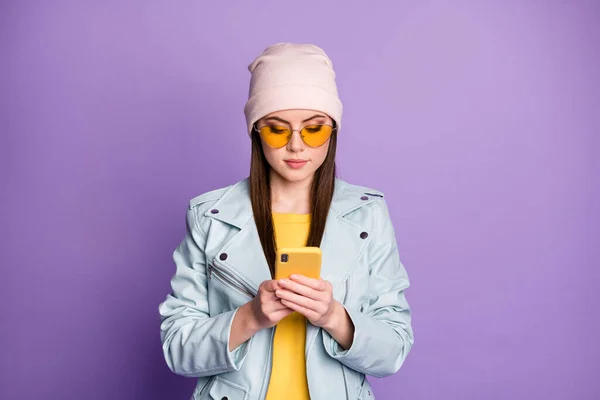 Photo of cool stylish pretty lady street clothes hold telephone hands read friends chatting messages wear sun specs casual hat blue modern style jacket isolated purple color background — Stock Photo, Image