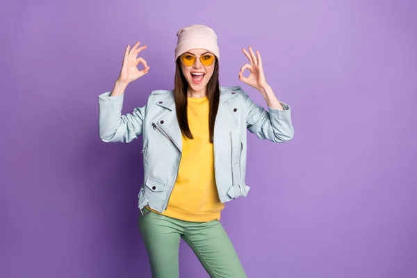 Retrato de chica enérgica loca disfrutar de excelentes anuncios promocionales recomiendan elegir decidir mostrar signo bien desgaste amarillo pantalones verdes aislados sobre fondo de color púrpura — Foto de Stock