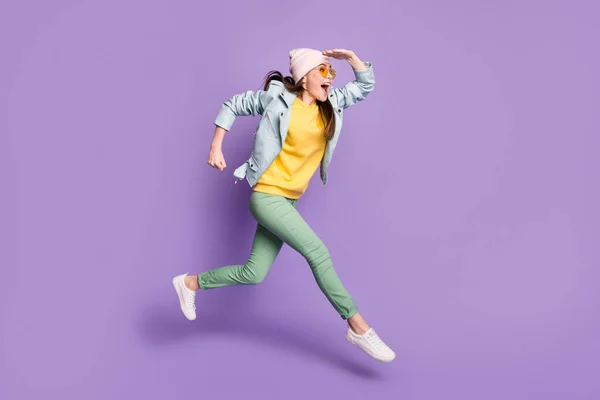 Foto lateral de perfil de tamaño completo de la chica alegre emocionada ver descubrir increíble salto correr rápido desgaste de la cabeza pantalones verdes pantalones chaqueta de cuero aislado color púrpura fondo —  Fotos de Stock