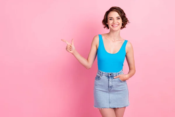 Foto av vackra ganska säker ung dam regissera finger tomt utrymme glänsande leende gör perfekt förslag slitage denim mini kjol blå tank-top isolerad rosa färg bakgrund — Stockfoto