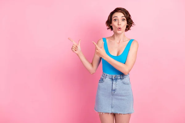 Tak dapat dipercaya. Foto menarik lucu gadis muda yang bersemangat gila terlihat mengarahkan jari kosong ruang diskon tak terduga memakai rok kecil denim biru singlet terisolasi warna latar belakang merah muda — Stok Foto