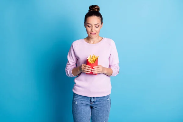 Portrait d'elle elle belle jolie affamée jolie fille affamée tenant dans la main manger frites fraîches chaudes savoureuses lèvres mordues isolé sur brillant vif fond de couleur bleue vibrante — Photo