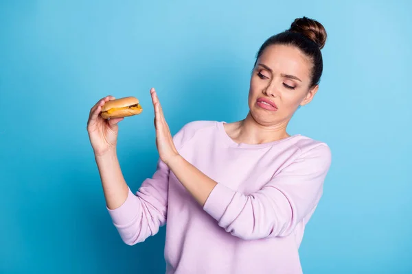 Bild av frustrerad flicka hålla hand vägra äta hamburgare grimace ansikte slitage violett elegant pullover isolerad över blå färg bakgrund — Stockfoto
