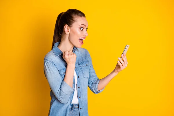 Foto de la chica emocionada sorprendida encantada uso del teléfono celular seguidores impresionados en las redes sociales suscriptores levantan los puños usan estilo ropa de moda elegante aislado brillo brillante color fondo — Foto de Stock