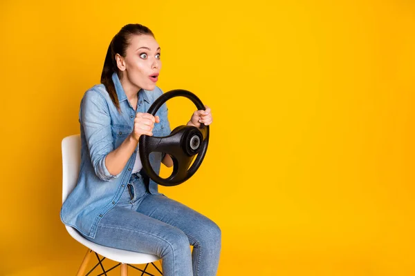 Foto de sorprendida chica divertida paseo coche mantener el volante sentarse silla aspecto copyspace impresionado desgaste estilo elegante moda jeans traje aislado sobre brillante brillo color fondo —  Fotos de Stock