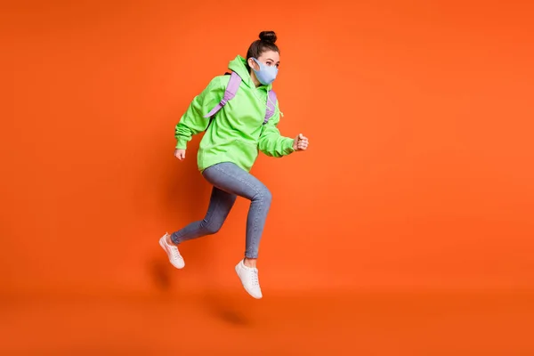 Foto retrato vista de corpo inteiro da menina saltando para cima correndo usando azul tecido máscara facial isolado no fundo de cor laranja vívida — Fotografia de Stock