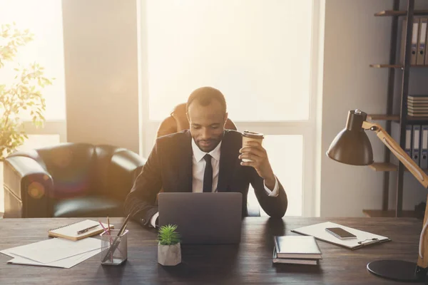 Foto von fröhlich gut aussehende dunkelhäutige Geschäftsmann Agent Kerl Notizbuch lesen Corporate Report Versicherungsmakler trinken Kaffee Uhr Webinar tragen Anzug sitzend Stuhl moderne Innenraum Büro drinnen — Stockfoto