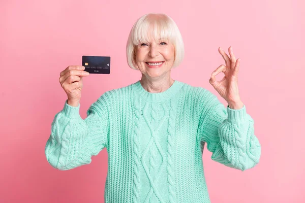 Foto Porträt der alten Dame blonde Haare halten Bankkarte lächeln okay Zeichen lächeln isoliert auf pastellrosa Hintergrund — Stockfoto