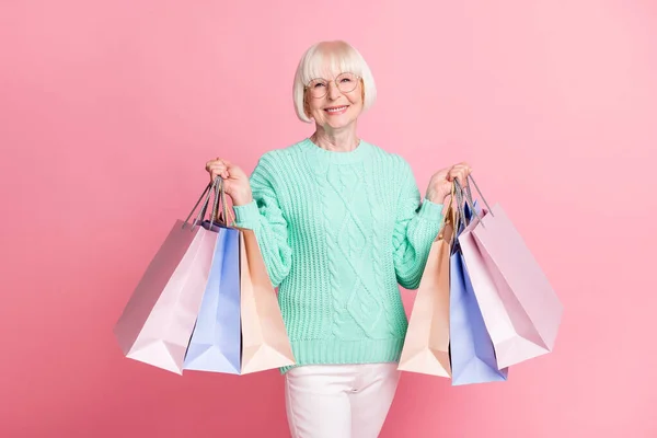 Foto retrato de pensionista femenina que tiene paquetes después de comprar en las tiendas el viernes negro aislado sobre fondo de color rosa pastel — Foto de Stock