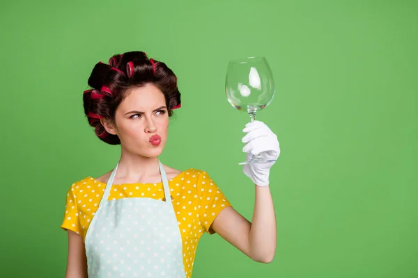 Foto di incerta cameriera ragazza sguardo bicchiere di vino controllo pulito usura giallo punteggiato retrò abito stile vintage isolato su sfondo di colore verde — Foto Stock