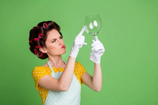 Φωτογραφία του αβέβαιου κοριτσιού έχουν κρασί γυαλί πλυντήριο πιάτων ελέγξτε καθαρό άγγιγμα λατέξ λευκά γάντια δάχτυλο φορούν κίτρινο διάστικτο φόρεμα κυλίνδρους μαλλιά απομονώνονται σε πράσινο χρώμα φόντο — Φωτογραφία Αρχείου