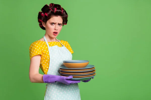 Porträt von ihr sie schön attraktiv glamourös überwältigt depressive Dienstmädchen tragen Lockenwickler halten in den Händen ordentlich ordentlich stapeln Teller isoliert über grünen Farbhintergrund — Stockfoto