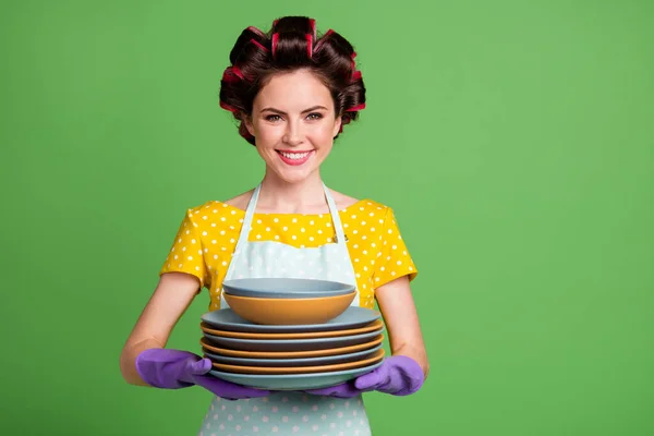 Photo of positive maid girl wash dishes after family party hold pile stack wear yellow dotted dress hair rollers isolated over green color background — Stock Photo, Image
