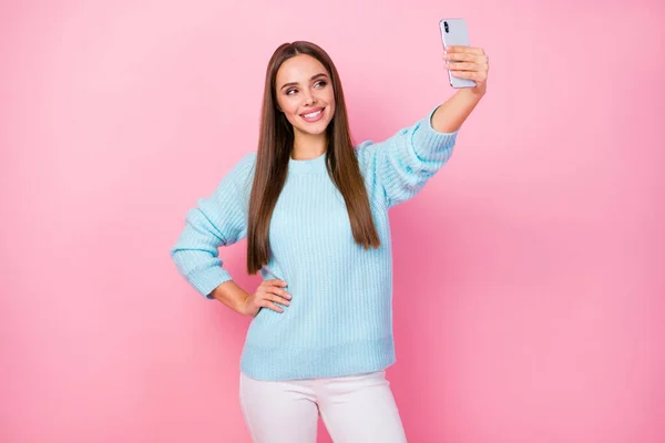Çekici, güzel bir bayanın el ele tutuşup gençlerin popüler blog kıyafetleri için selfie çektiği örülmüş mavi kazak beyaz pantolon izole edilmiş pastel pembe arka plan. — Stok fotoğraf