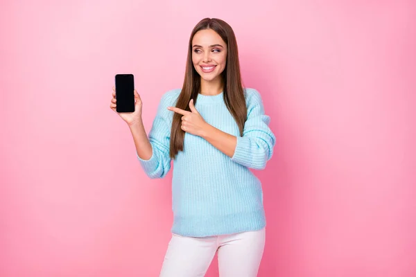 Foto van aantrekkelijke dame houden telefoon nieuw model adviseren laagseizoen prijs directe vinger touch screen slijtage gebreide blauwe trui witte broek geïsoleerde pastel roze kleur achtergrond — Stockfoto