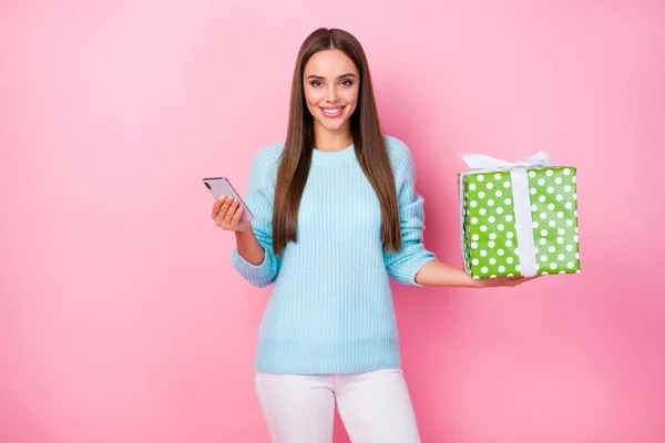 Foto der hübschen Dame halten Telefonscheck chattende Kunden Express-Lieferservice große Geschenkbox Hand tragen gestrickte blaue Pullover weiße Hosen isoliert pastellrosa Hintergrund — Stockfoto