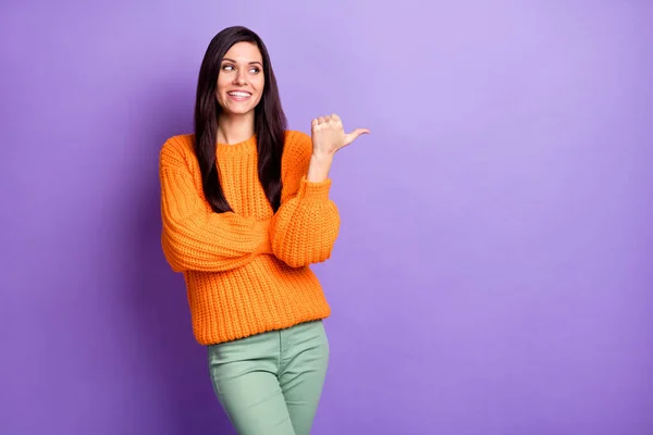 Kuva muotokuva nainen yllään oranssi pusero osoittaa etsivät tyhjä tila sormi hymyillen eristetty eloisa violetti väri tausta — kuvapankkivalokuva