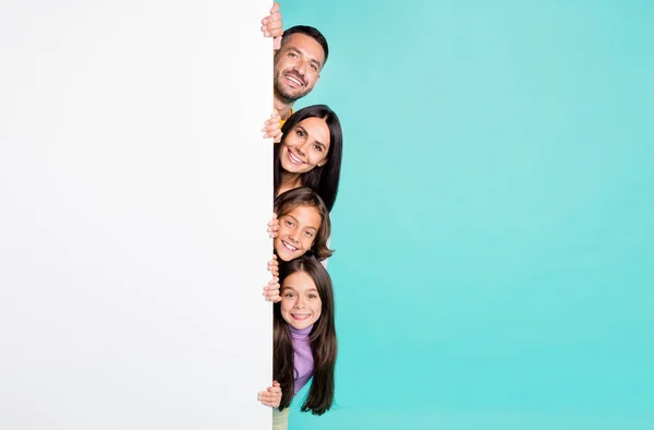 Foto ritratto di famiglia piena con bambini piccoli picco dal lato del manifesto banner bianco isolato su sfondo di colore turchese vivido — Foto Stock