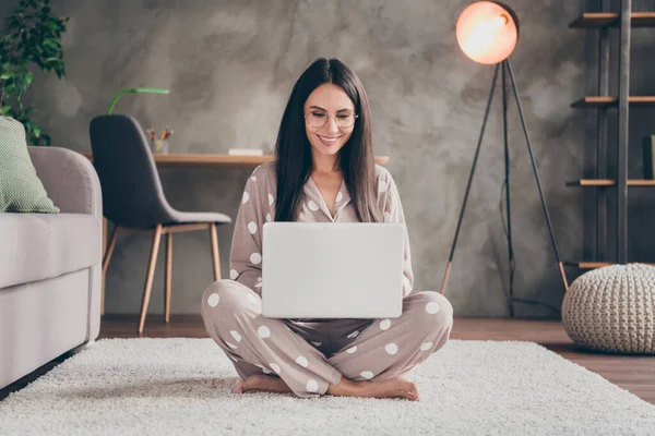 Zdjęcie miłej słodkiej dziewczyny siedzieć na dywanie typu laptop nosić okulary pijama w domu — Zdjęcie stockowe