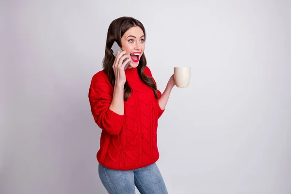 Foto retrato de menina maravilhada segurando caneca com bebida falando no celular isolado no fundo cor cinza pastel — Fotografia de Stock