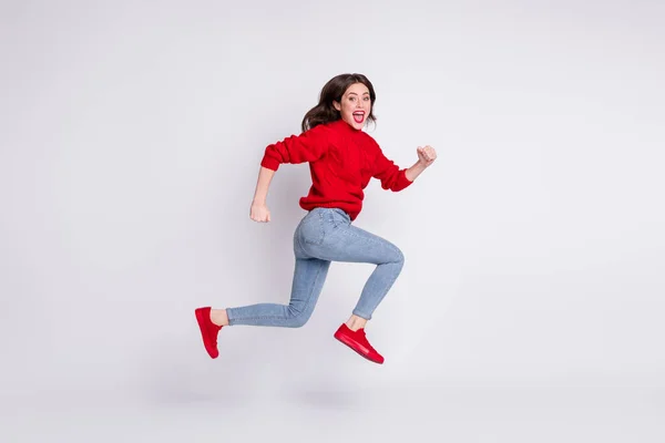 Tamanho total do corpo foto de pular menina em jeans camisola vermelha rindo alegre isolado no fundo cor pastel cinza — Fotografia de Stock