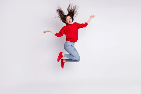 Full length body size photo of jumping girl rzucanie włosów śmiejąc się w czerwonym sweter dżinsy izolowane na szarym pastelowym tle kolor — Zdjęcie stockowe