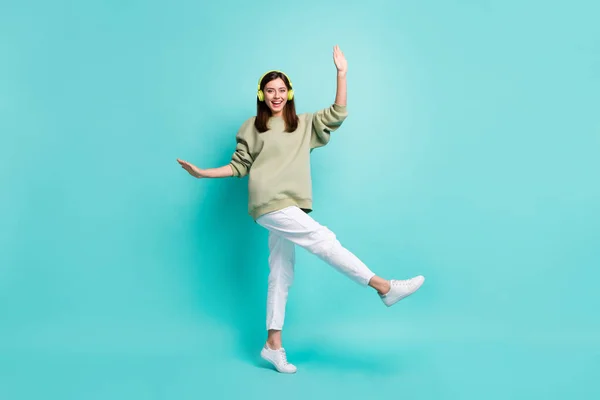 Retrato fotográfico de larga duración de la alegre bailarina con auriculares parados en una pierna aislada sobre un fondo de color verde azulado — Foto de Stock