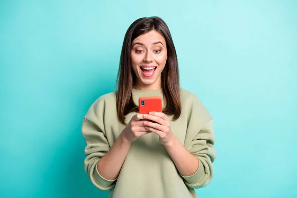 Foto retrato de menina animado com boca aberta segurando telefone em duas mãos isoladas no fundo colorido teal vívido — Fotografia de Stock