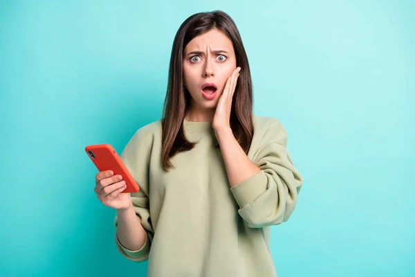 Portrait photo de femme effrayée confuse avec la bouche ouverte tenant le téléphone dans une main isolée sur fond turquoise vif — Photo