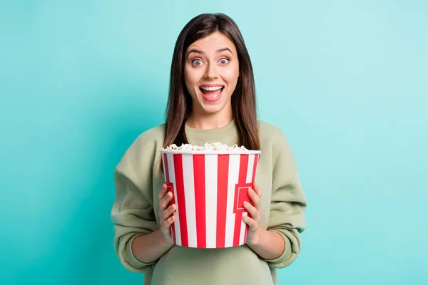 Photo portrait of screaming woman holding large popcorn bucket with two hands isolated on vivid cyan colored background — Stock Photo, Image