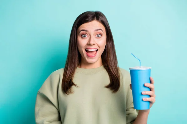鮮やかなターコイズ色の背景に隔離された青いプラスチック製のカップを保持している唖然とした女性の写真 — ストック写真