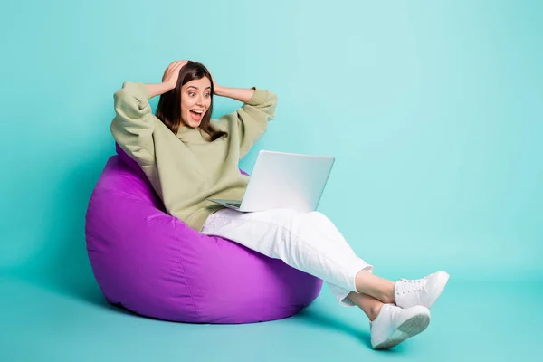 Foto potret seluruh tubuh pemandangan wanita menjerit kagum dengan laptop memegang kepala dengan dua tangan duduk di kursi ungu terisolasi pada latar belakang berwarna cerah sian — Stok Foto