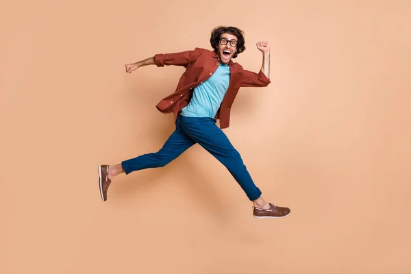 Foto ritratto vista corpo pieno di ridere ragazzo in esecuzione saltando isolato su sfondo color beige pastello — Foto Stock