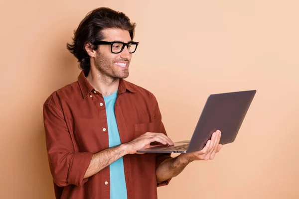 Фотопортрет людини, що тримає ноутбук в руці, ізольований на пастельному бежевому кольоровому фоні — стокове фото