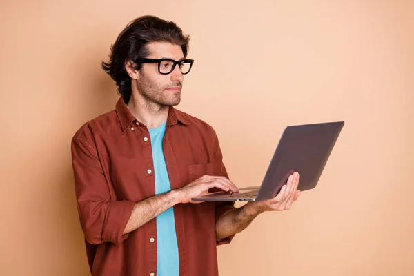 Perfil foto do cara sério segurar computador olhar tela desgaste óculos marrom t-shirt isolado cor bege fundo — Fotografia de Stock
