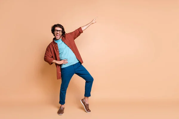Volledige lengte foto van man geven vinger omhoog open mond slijtage specs bruin t-shirt broek schoenen geïsoleerde beige kleur achtergrond — Stockfoto