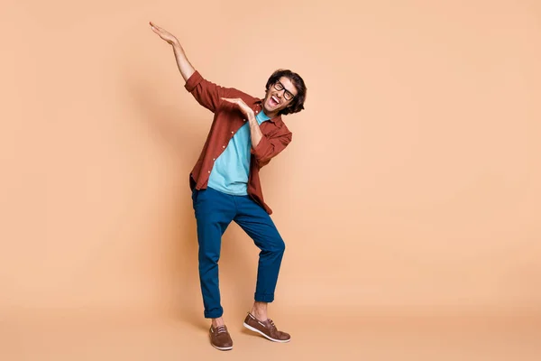 Full length foto van guy dance raise handen hebben plezier dragen bril bruin t-shirt broek schoenen geïsoleerde beige kleur achtergrond — Stockfoto