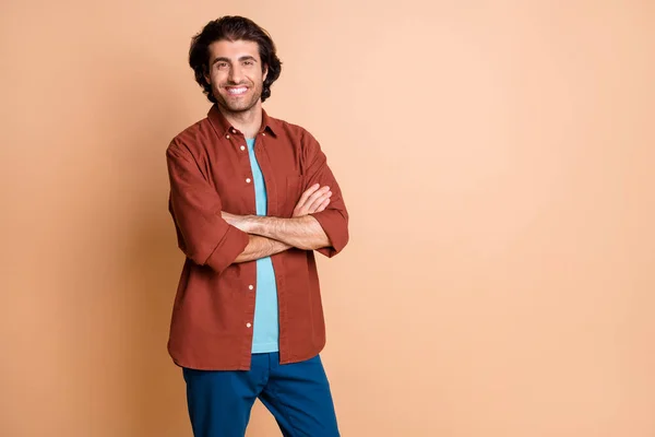 Foto di giovane uomo auto-assicurato guardare fotocamera mani piegate fiducioso indossare marrone t-shirt pantaloni blu isolato colore beige sfondo — Foto Stock