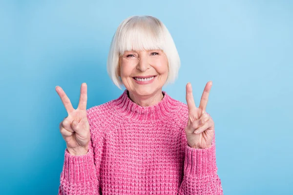 Foto portrét šťastné staré dámy zobrazující dvě V-značky izolované na pastelově modrém pozadí — Stock fotografie
