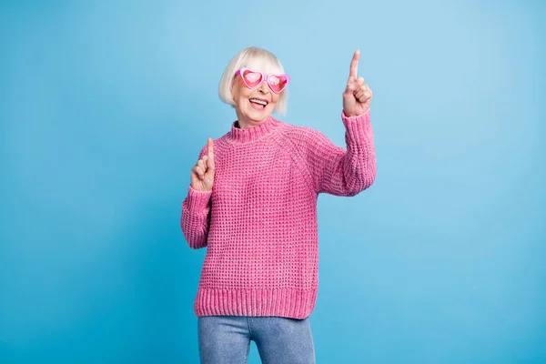 Fénykép portré aranyos idős hölgy ujjal felfelé táncoló visel rózsaszín szemüveget elszigetelt pasztell kék színű háttér — Stock Fotó