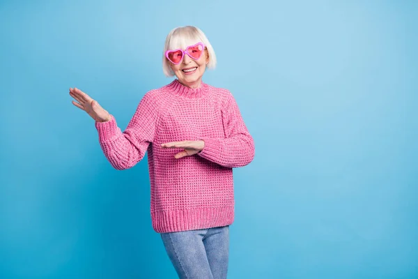 Pastel mavi arka planda pembe gözlüklerle dans eden yaşlı bir kadının fotoğrafı. — Stok fotoğraf