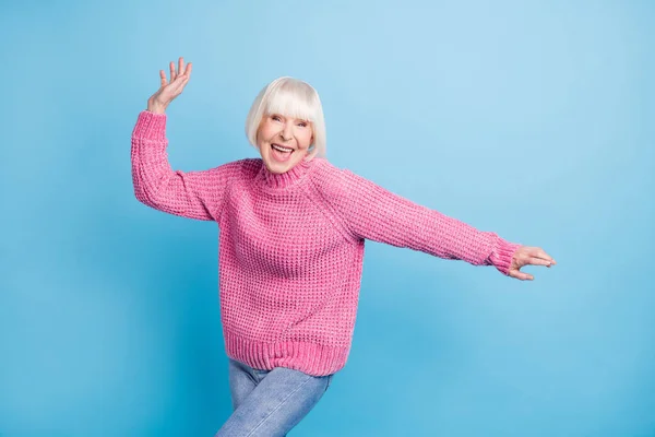 Photo portrait of cheerful old woman dancing isolated on pastel blue colored background