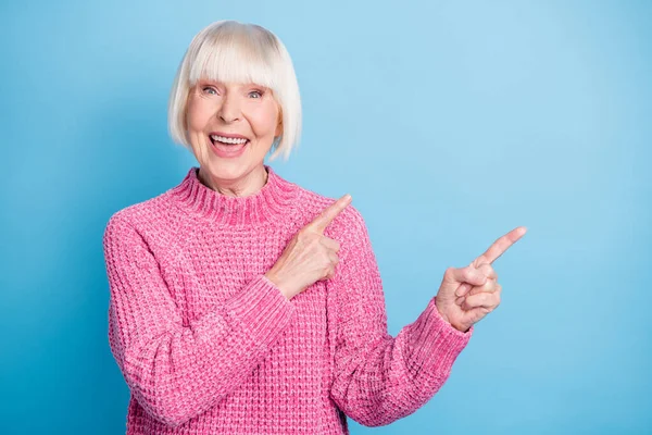 Фотопортрет взволнованной пожилой женщины с открытым ртом, указывающей двумя пальцами на пустое место, изолированное на пастельно-голубом фоне — стоковое фото